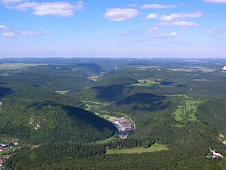 Luftaufnahme des Bäratals Richtung Albtrauf im Nordwesten. Das Tal teilt den Großen Heuberg in eine höhere westliche (links) und eine niedrigere östliche Hochfläche (rechts). Letztere ist auch als „Hardt“ bekannt. Am Horizont erkennt man die durch unruhiges Relief geprägten Balinger Berge mit den höchsten Gipfeln der Schwäbischen Alb.