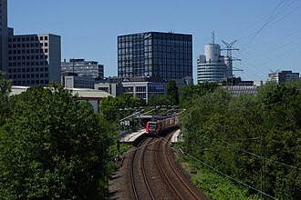 Triebzug der DB-Baureihe 423 als S-Bahn der Linie S 4 von Kronberg nach Langen im Haltepunkt Eschborn Süd; darüber das Gebäude The Cube der Deutschen Börse
