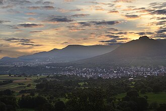 Albtrauf, Mittlere Schwäbische Alb, gesehen vom Osthang (575 m) des Jusibergs (672,6 m). Die Orte sind Neuffen und Beuren. Den Albtrauf bilden Hohenneuffen (745,4 m), Bassgeige (735,6 m), westlich von Beuren der Engelberg (527,2 m) und weiter hinten der Teckberg (774,8 m) mit vorgelagertem Schwäbischen Vulkan Hohenbol (602,2 m). Am Albtrauf liegt ausladender Hangschutt. Das Vorland mit den beiden Orten ruht auf Schichten des Braunen Jura.